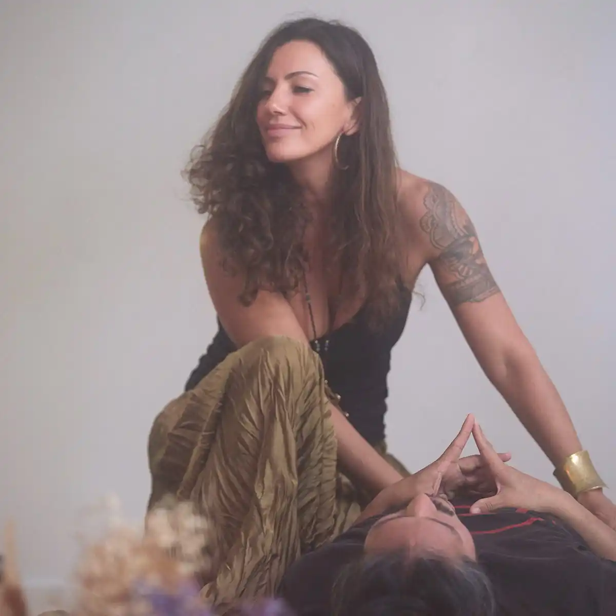 Bianca Be smiling during an energy healing session with client lying down, hands placed on hips for grounding